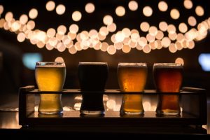 a flight of several different beers with blurred lights in the background